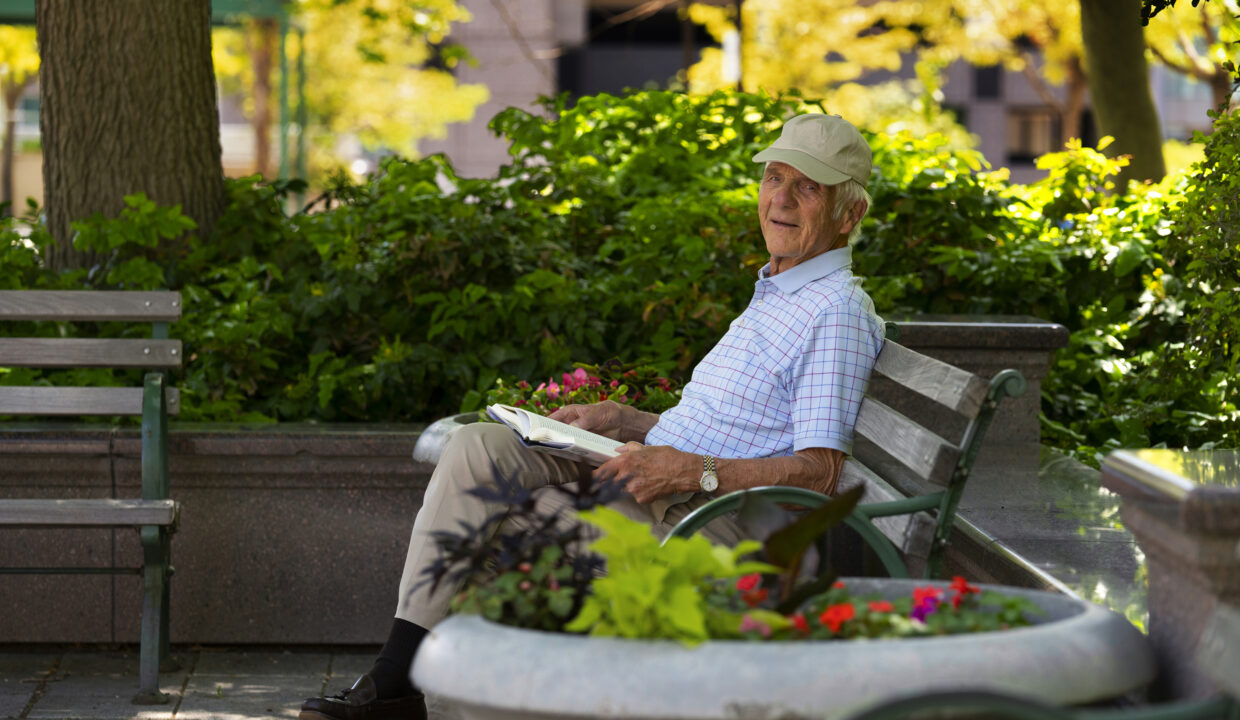 senior-man-sitting-bench-outdoors-reading-book